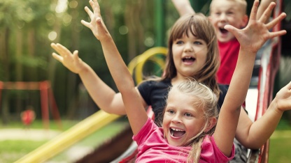 Kinder rutschen auf einem Spielplatz