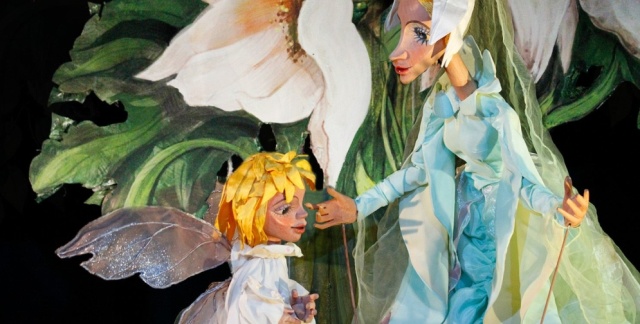 Two fairy puppets nect to a white lilly and greenery