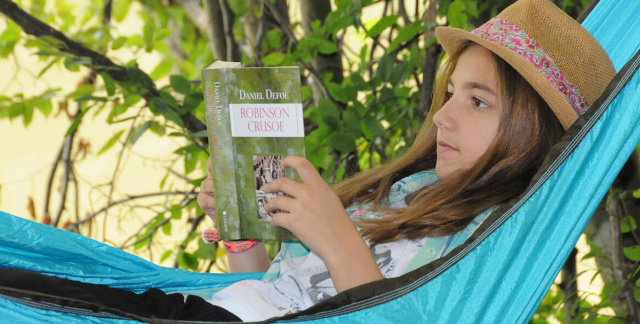 Mädchen liest Buch in einer Hängematte