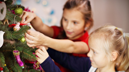 Kinder in der Weihnachtswerkstatt Zwei Mädchen schmücken Tannen