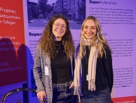 Zwei Frauen stehen lächelnd an einem Stand